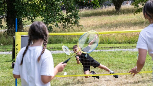 A family enjoy playing badminton on the lawn at Penrhyn Castle during the Summer of Play